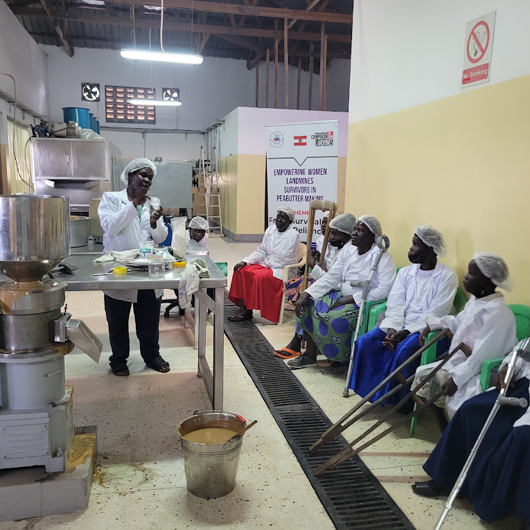 A UIRI facilitator demonstrates peanut butter processing to women trainees in Lira